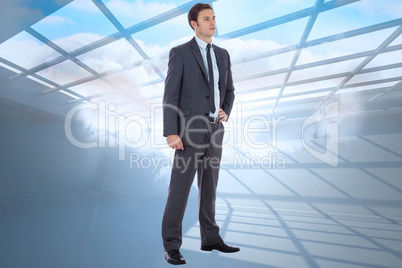 Composite image of serious businessman with hand on hip