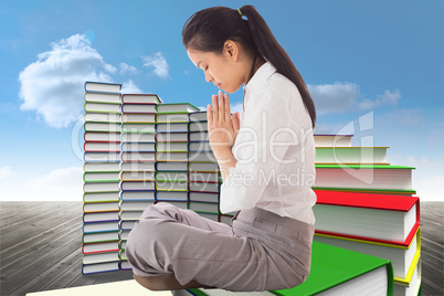 Composite image of businesswoman sitting in lotus pose