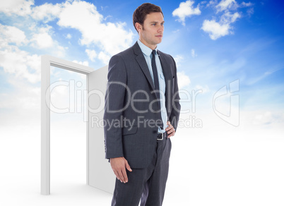 Composite image of serious businessman with hand on hip