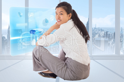 Composite image of businesswoman sitting cross legged smiling