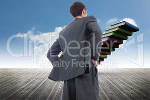 Composite image of businessman standing with hands on hips
