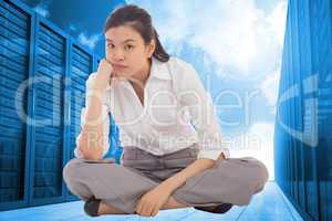 Composite image of grumpy businesswoman sitting cross legged