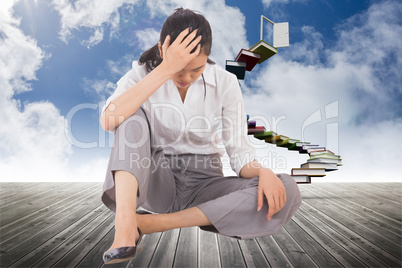 Composite image of depressed businesswoman sitting with hand on