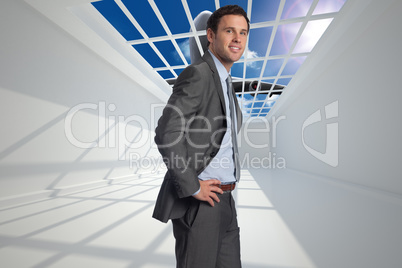 Composite image of smiling businessman with hands on hips