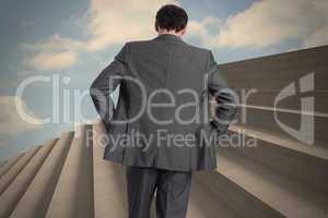 Composite image of businessman with hands on hips