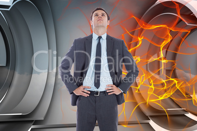 Composite image of serious businessman with hands on hips