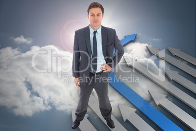 Composite image of stern businessman standing with hand on hip