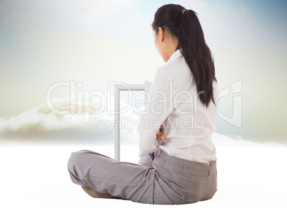 Composite image of businesswoman sitting cross legged