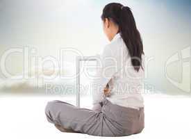 Composite image of businesswoman sitting cross legged