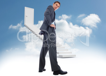 Composite image of serious businessman with hands on hips