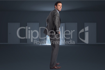 Composite image of smiling businessman with hands on hips