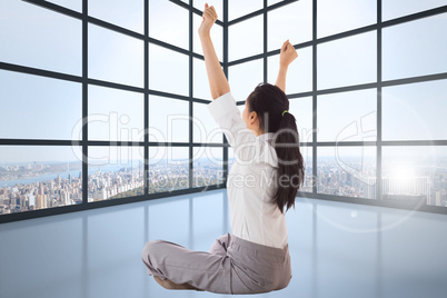 Composite image of businesswoman sitting cross legged cheering