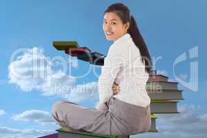 Composite image of businesswoman sitting cross legged smiling