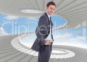 Composite image of smiling businessman with hands on hips