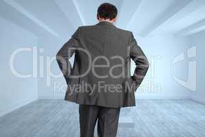 Composite image of businessman with hands on hips