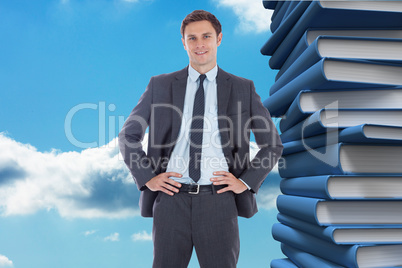 Composite image of smiling businessman with hands on hips