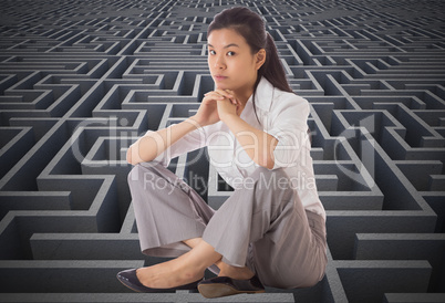 Composite image of businesswoman sitting cross legged with hands