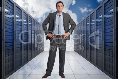 Composite image of smiling businessman with hands on hips