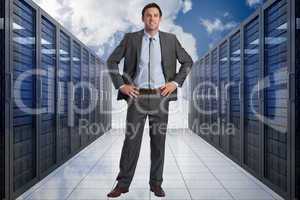 Composite image of smiling businessman with hands on hips