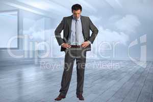 Composite image of serious businessman with hands on hips