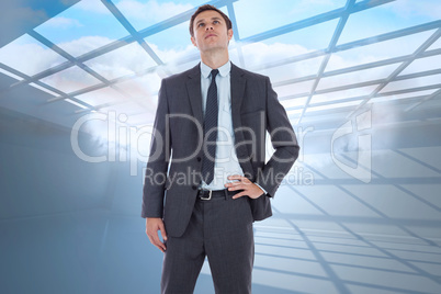 Composite image of serious businessman with hand on hip