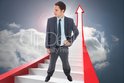 Composite image of stern businessman standing with hand on hip