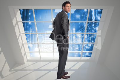 Composite image of businessman with hands on hips