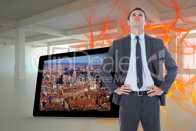 Composite image of serious businessman with hands on hips