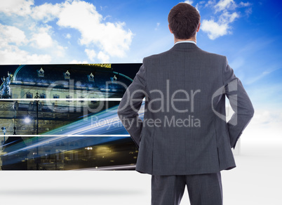 Composite image of businessman standing with hands on hips