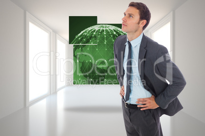 Composite image of serious businessman standing with hands on hi