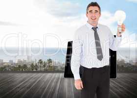 Composite image of man holding a light bulb