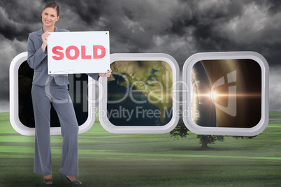 Composite image of happy real estate agent with sold sign