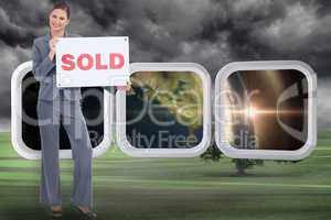 Composite image of happy real estate agent with sold sign