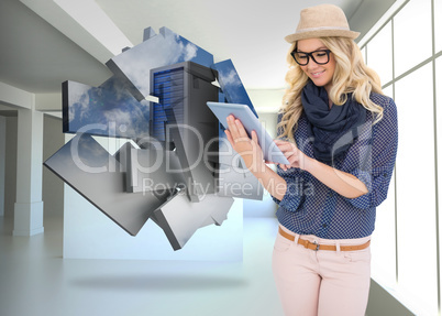 Composite image of smiling trendy blonde using tablet computer