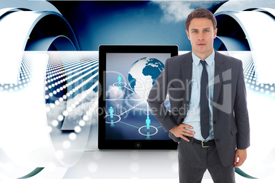 Composite image of serious businessman standing with hand on hip