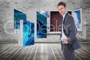 Composite image of serious businessman with hands on hips