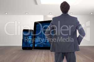 Composite image of businessman standing with hands on hips