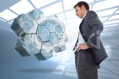 Composite image of stern businessman standing with hands on hips