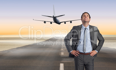 Composite image of smiling businessman with hand on hip