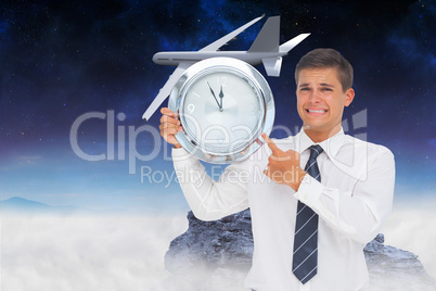 Composite image of anxious businessman holding and showing a clo