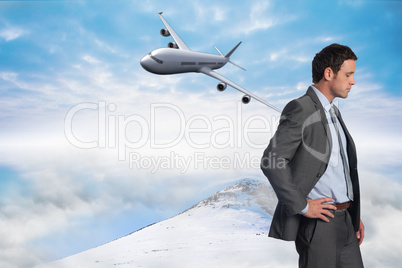 Composite image of serious businessman with hand on hip