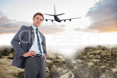 Composite image of stern businessman with hands on hips