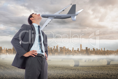 Composite image of cheerful businessman with hands on hips