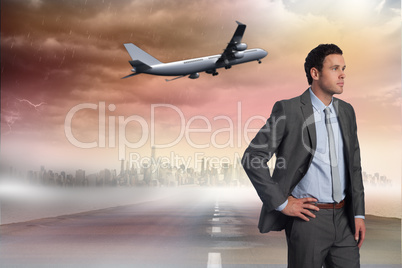 Composite image of businessman with hand on hip