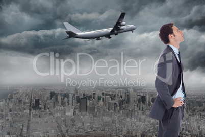 Composite image of serious businessman with hands on hips