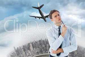 Composite image of thinking businessman holding pen