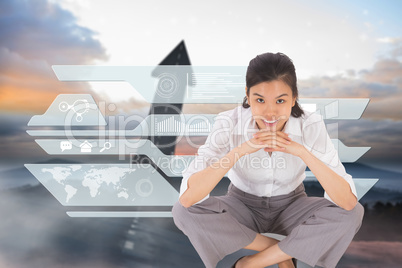 Composite image of smiling businesswoman sitting cross legged