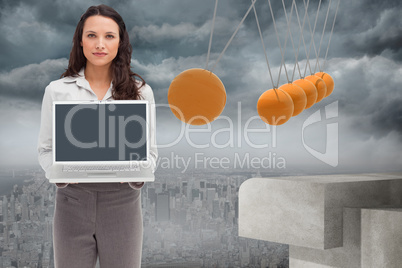 Composite image of brunette woman standing while showing a lapto
