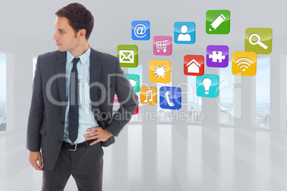 Composite image of serious businessman standing with hand on hip