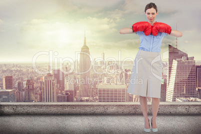 Composite image of tough businesswoman posing with red boxing gl